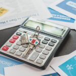 A calculator and real estate flyers depicting financial planning for home buyers.